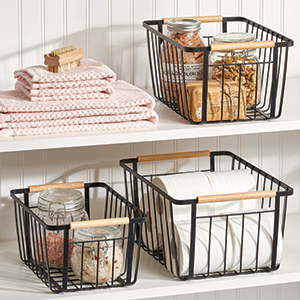 black wire baskets holding glass jars and toilet paper, towels on white shelves with white wood wall