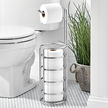 bathroom setting, white toilet, chrome tp holder, plant in basket, gray floor, white walls